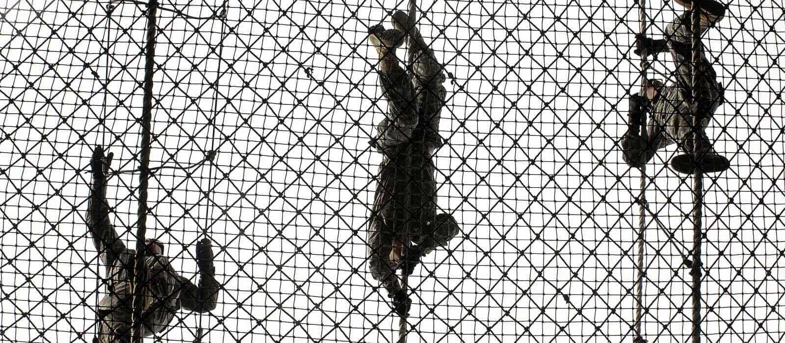 US Soldiers crawling across a rope bridge