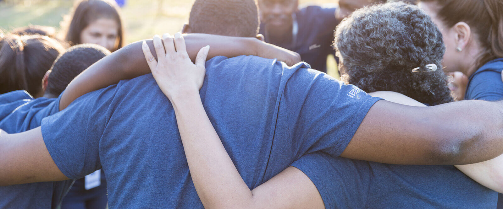Ten happy community volunteers hugging in a circle