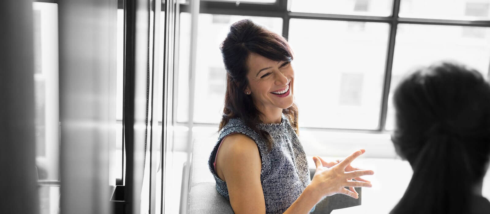 Two smiling people enjoying a lighthearted conversation in an office area