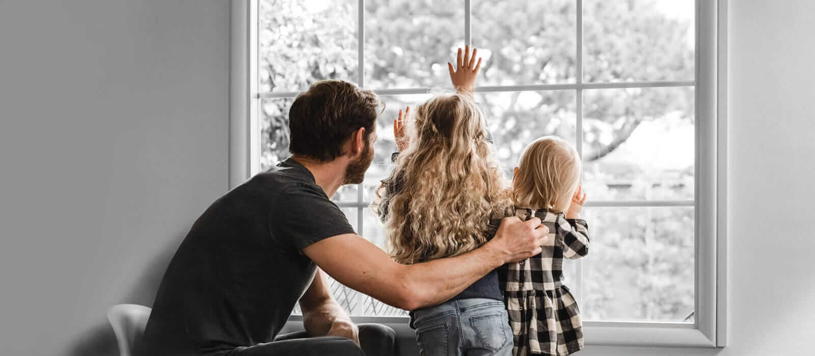 Father holding two kids up to a window.