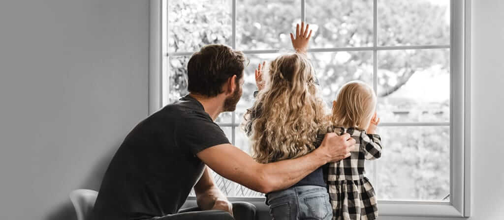 A family looking out a window on a winter landscape.