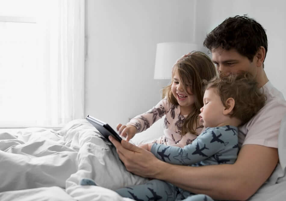 Father with children in bed enjoying time together with the confidence of a Command checking account.