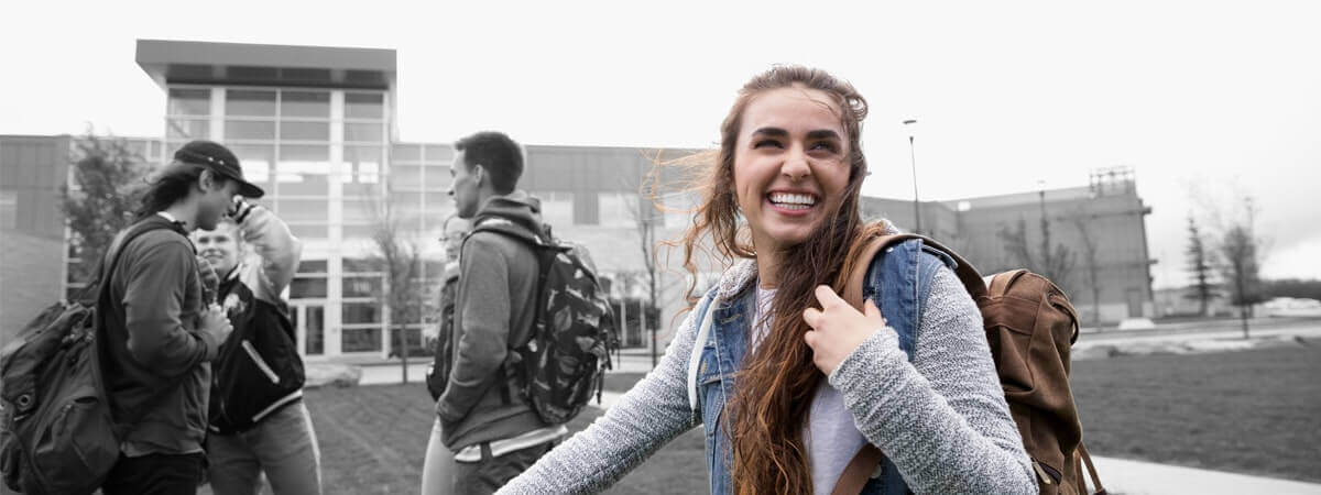 A teenager is laughing excitedly as she heads into school with her friends