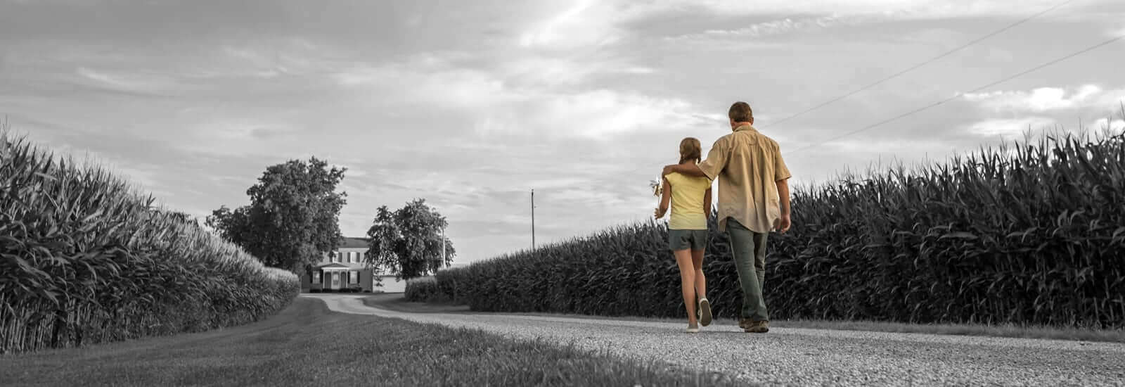 A father and his daughter are walking back to their house after spending time in their farm