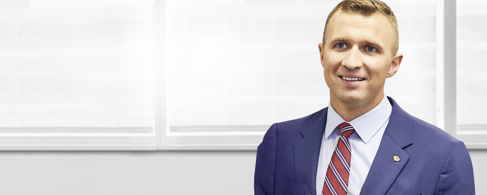 A man in a blue suit smiling and looking towards the camera.