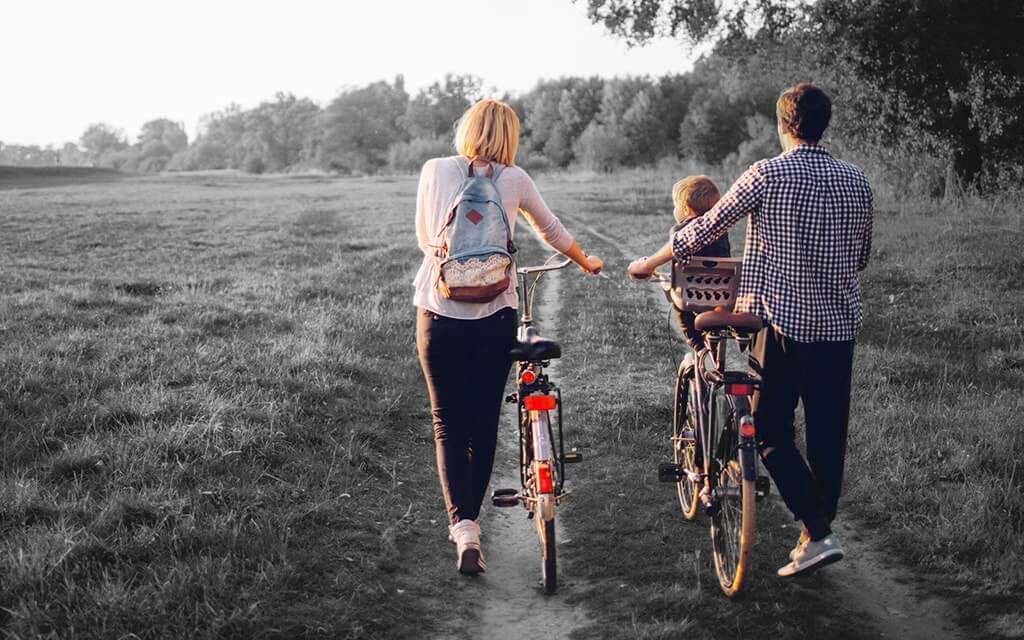 Greyed out image with family walking bikes and child enjoying life protected by insurance
