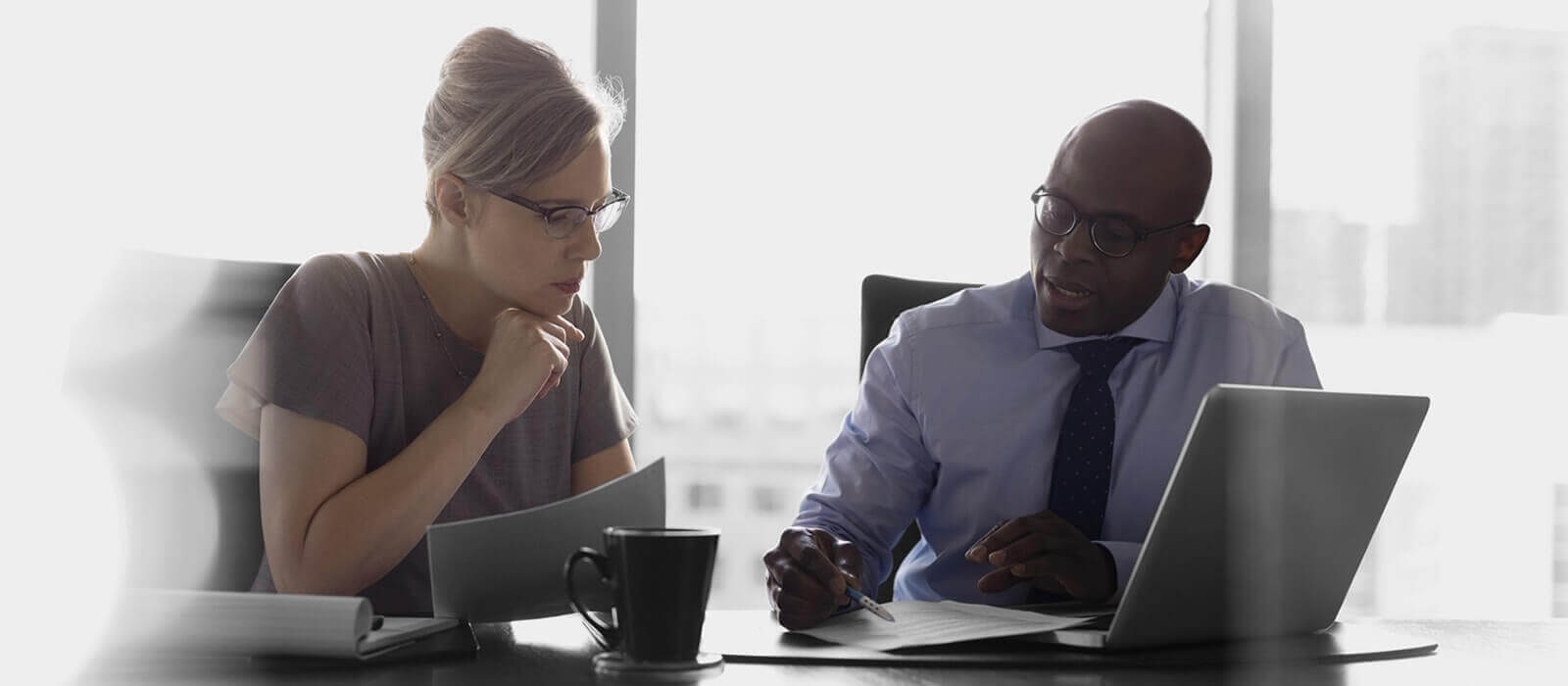 A man and woman discussing financial documents at a desk.