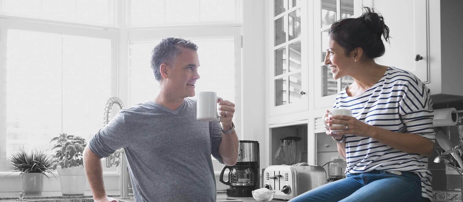 Image of a couple sitting in kitchen drinking coffee together.