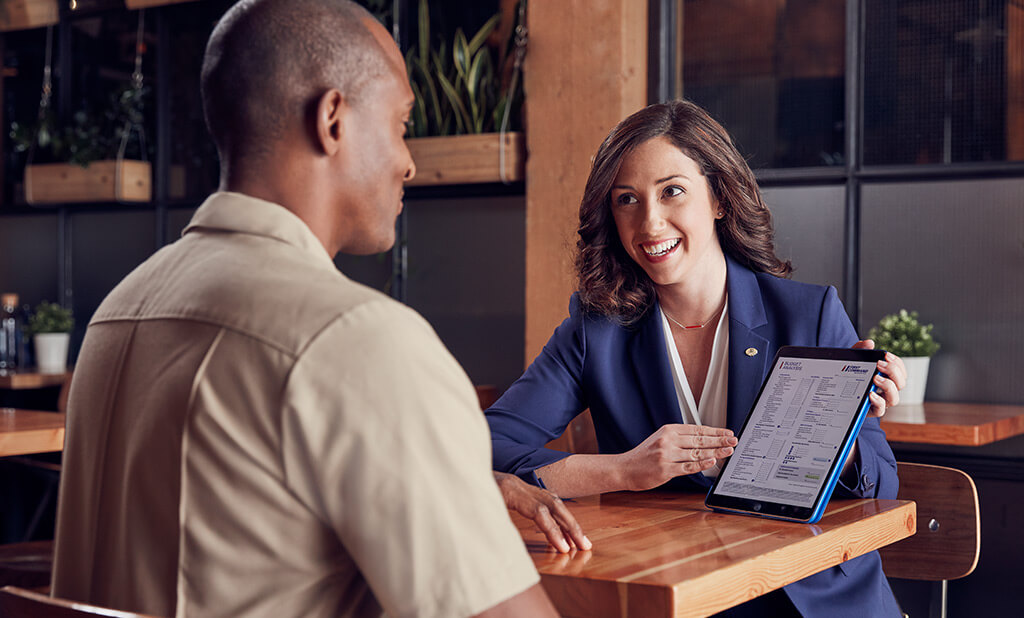 A First Command advisor explaining a document to a US military soldier in a cafe.